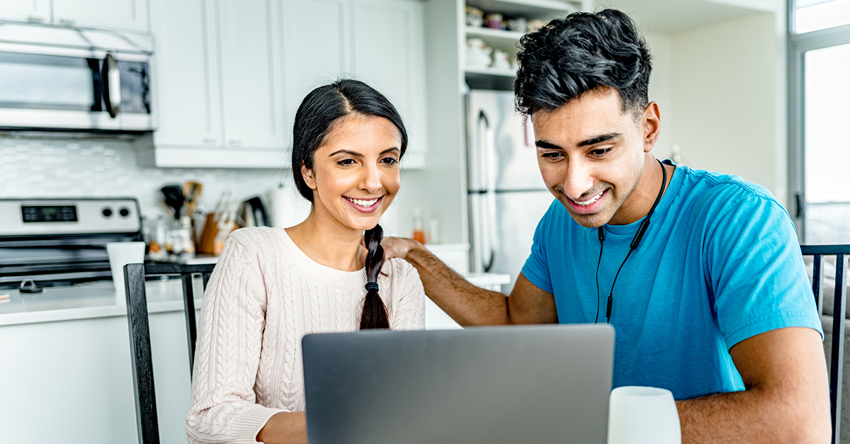 A millennial couple at home on their laptop